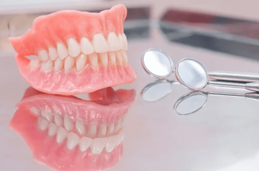 complete set of dentures sitting on a reflective surface with two dental mirrors restorative dentistry dentist in Washington DC